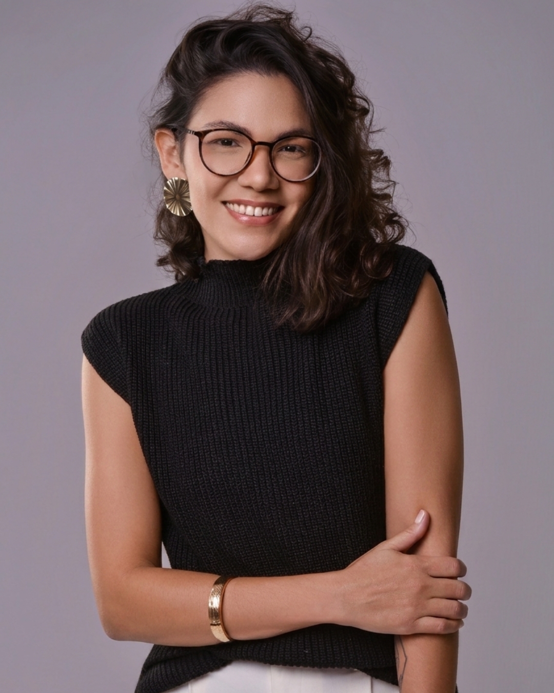 Virgínia, de óculos e blusa preta, sorrindo em retrato de estúdio